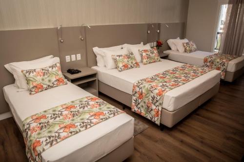 a room with three beds with floral sheets at Jardins de Jurema Convention & Termas Resort in Iretama