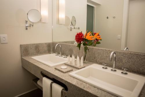 a bathroom with two sinks and a large mirror at Jardins de Jurema Convention & Termas Resort in Iretama