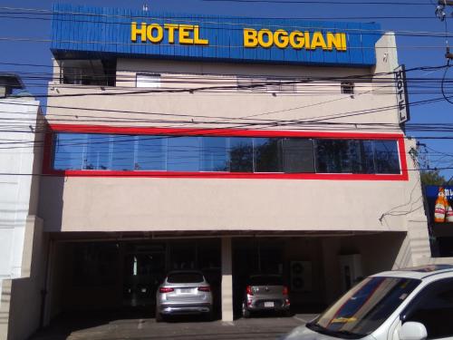 a hotel with cars parked in front of a building at Hotel Boggiani in Asunción
