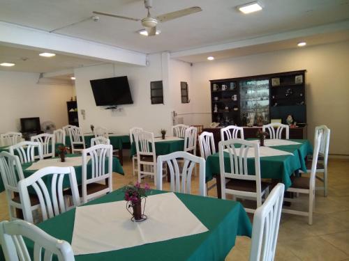 Un comedor con mesas verdes y sillas blancas. en Hotel Boggiani, en Asunción