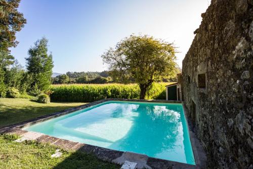 a swimming pool in a yard next to a stone wall at Casa do Retiro in Ponte de Lima