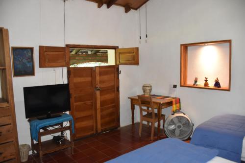a bedroom with a bed and a television and a desk at The Mayan Grouper in Suchitoto