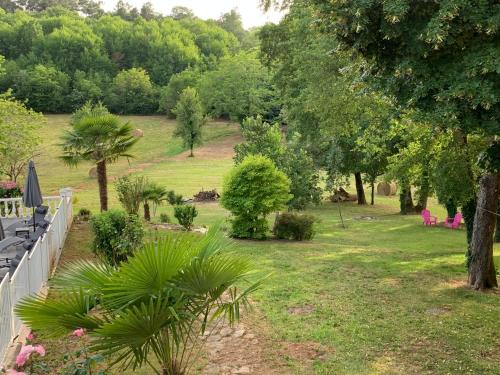 a garden with trees and grass and a fence at La biche au bois piscine chauffee jacuzzi in Cazals