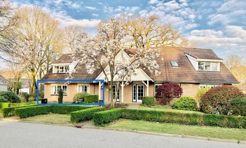 a house with a brown roof and flowering trees at De Bonte Specht in Nijverdal