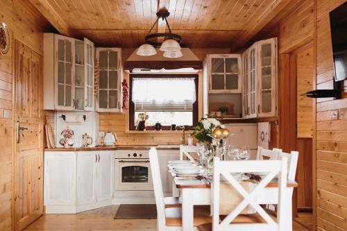 a kitchen with white cabinets and a table and chairs at BESKIDZKA CHAŁUPKA in Łękawica