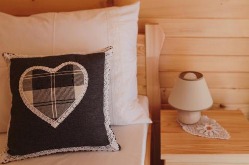 łóżko z czarno-białą poduszką i lampą w obiekcie BESKIDZKA CHAŁUPKA w mieście Łękawica