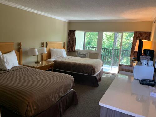 a hotel room with two beds and a balcony at Okanagan Royal Park Inn by Elevate Rooms in Vernon