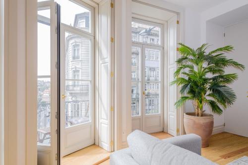 a living room with a potted plant and large windows at BOUTIQUE Rentals-Kihara’s Ribeira Apt with great views in Porto