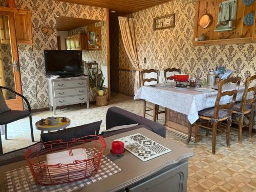 a living room with a table and chairs and a television at L’Eterle in Aillon-le-Jeune