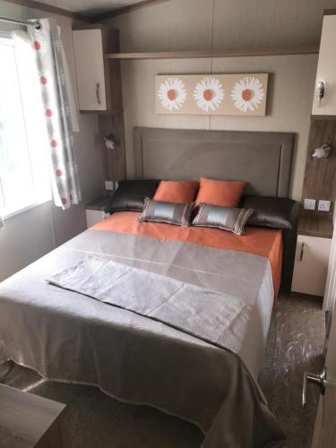 a bedroom with a large bed with orange pillows at Lakes Retreat in Millom