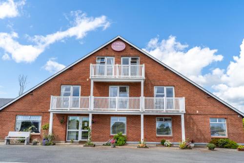 a red brick building with a balcony and a clock at Coral Gables Guesthouse & Campsite in Rosslare