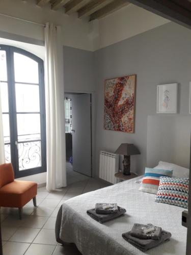 a white bedroom with a bed and a window at Le Barrème in Arles