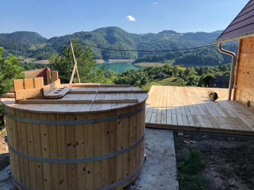 a wooden barrel with a deck and mountains in the background at Zaovinska idila in Bjeluša