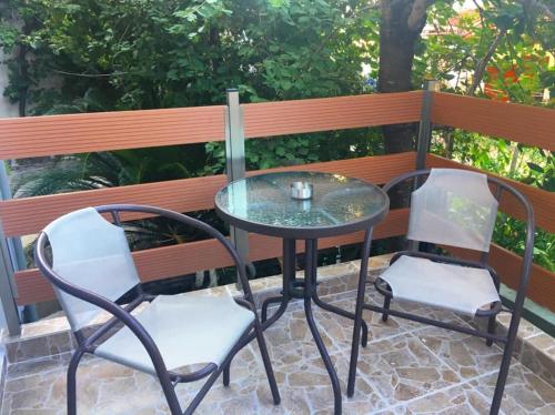 two chairs and a glass table and chairs on a patio at Almira - rooms to let in Nea Roda