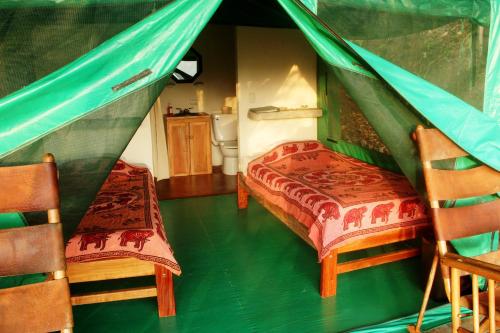 a bedroom with a bed and two chairs in a tent at Luna Lodge in Carate