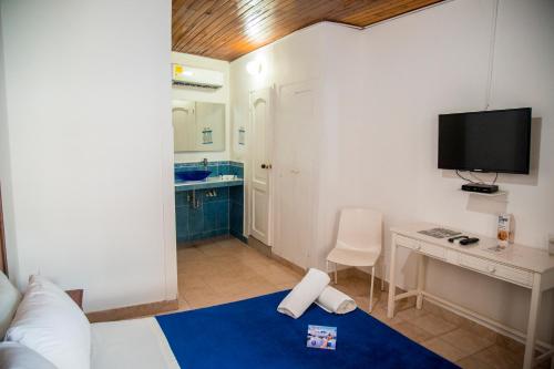 a room with a bed and a desk with a television at La Ballena Azul Hotel in Taganga