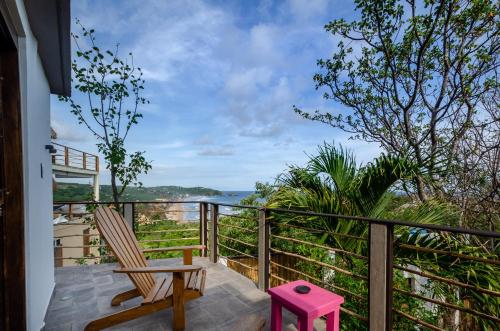 a balcony with a chair and a pink stool at Casa Kalmar in Zipolite