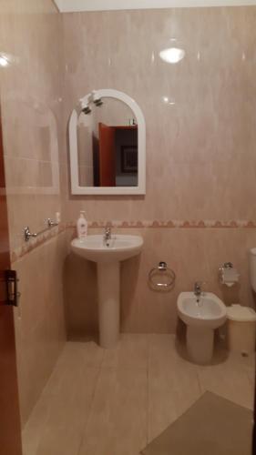 a bathroom with a sink and a toilet and a mirror at Alojamentos S.José in Atouguia da Baleia