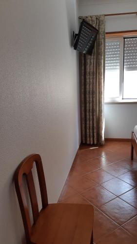 a dining room with a table and a chair and a window at Alojamentos S.José in Atouguia da Baleia