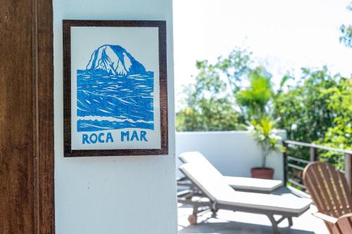 a sign on a wall next to two chairs on a porch at Casa Kalmar in Zipolite