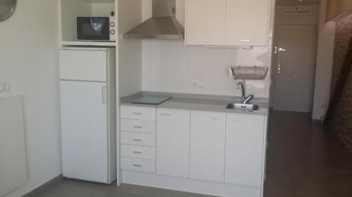 una cocina blanca con armarios blancos y fregadero en Acogedor apartamento con vistas al mar. en Bellreguart