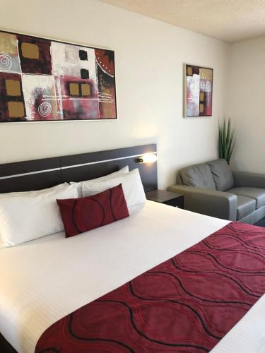 um quarto de hotel com uma cama grande e um sofá em Golden West Motor Inn em Dubbo