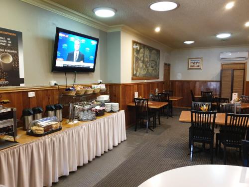 a dining room with tables and a tv on the wall at Best Western Endeavour Motel in Maitland
