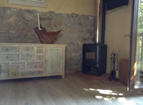 a living room with a tv and a stone wall at La Cabaña de Bernardina in Sotres