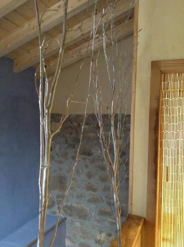 a tree in a room with a stone wall at La Cabaña de Bernardina in Sotres