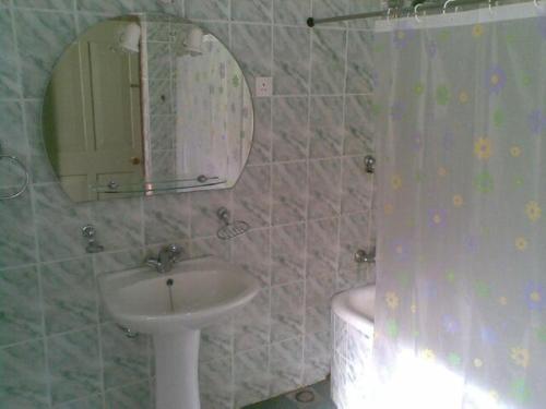 a bathroom with a sink and a mirror and a toilet at Devon Fall Cottage in Dimbula