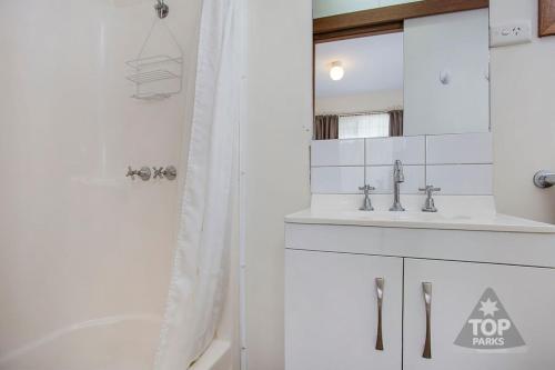 a white bathroom with a tub and a sink at Great Ocean Road Tourist Park in Peterborough