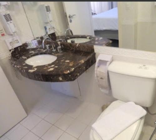 uma casa de banho com um WC, um lavatório e um espelho. em Loft Confortável e Moderno em São Paulo