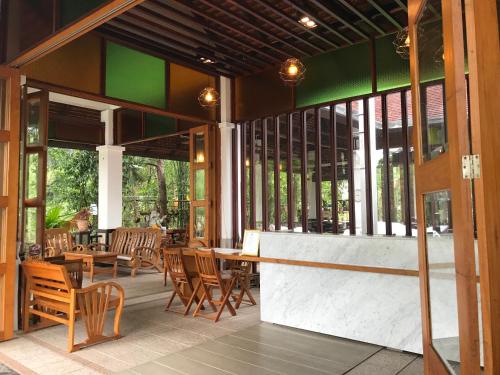 a restaurant with wooden chairs and tables and windows at Tak Andaman Resort & Hotel in Tak