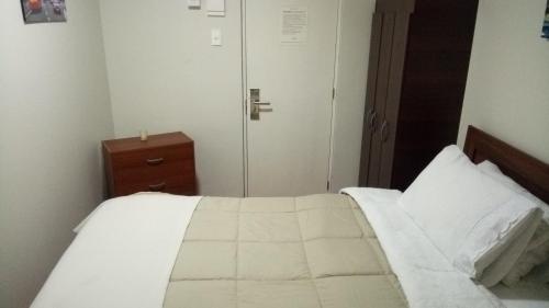 a bedroom with a white bed and a closet at Hostal Los Castaños in Viña del Mar