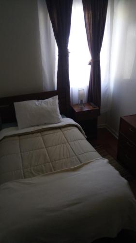 a bedroom with a white bed and a window at Hostal Los Castaños in Viña del Mar