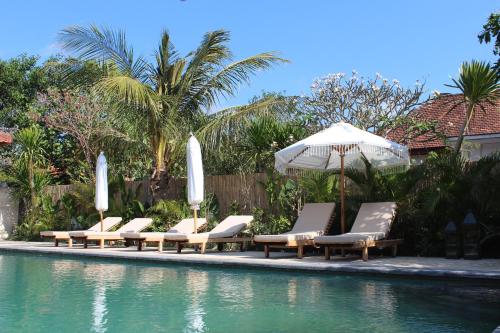 a group of lounge chairs and an umbrella next to a pool at The Inn Possible in Uluwatu