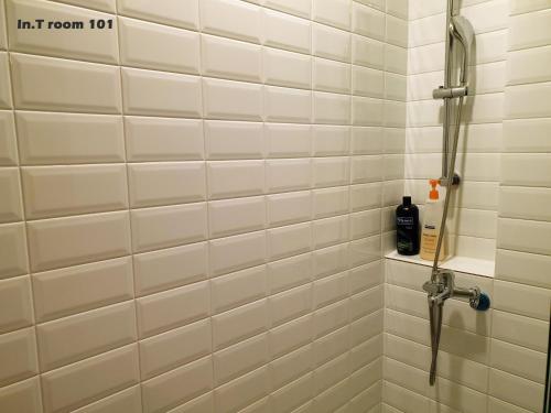 a shower in a bathroom with white tiled walls at In.T in Tainan