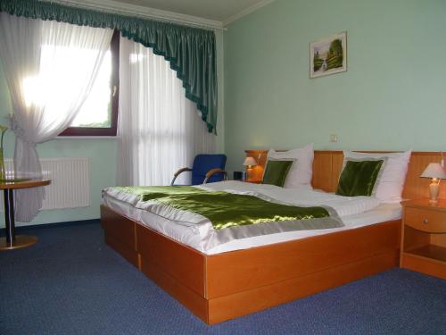 a bedroom with a bed with a green blanket on it at Hotel Restauracja Tawerna Gliwice in Gliwice