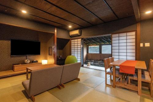 a living room with a dining table and a television at Ishinoya Izunagaoka - TKP Hotels & Resorts in Izunokuni