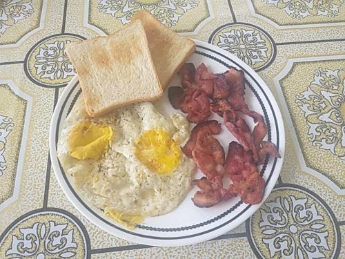a plate of breakfast food with eggs bacon and toast at Soul Travellers Dagatan Guesthouse in Badian