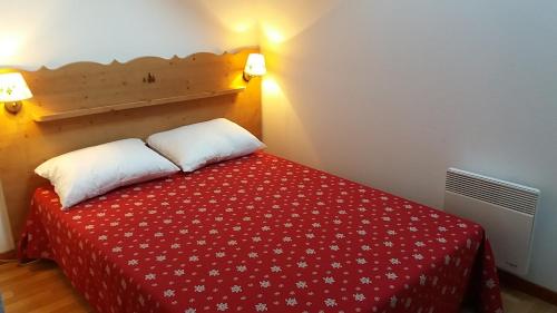 ein Schlafzimmer mit einem Bett mit einer roten Decke in der Unterkunft Beau T3 ensoleillé au pied des pistes in Arvieux