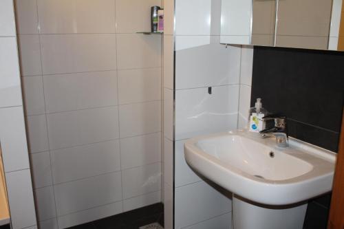 een witte badkamer met een wastafel en een douche bij De Rheezermars in Rheeze