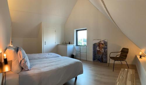 ein Schlafzimmer mit einem Bett und einem Stuhl im Dachgeschoss in der Unterkunft Ferias - cosy house in Brügge