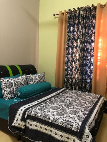 een bed met een zwart-witte deken en een gordijn bij Villa Ungu Homestay in Kubang Kerian