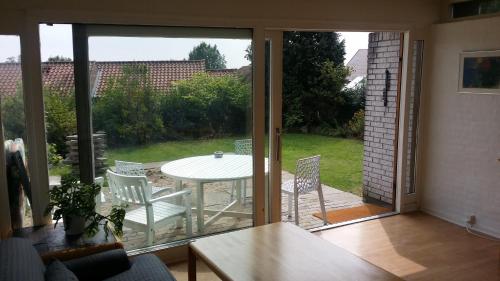 een woonkamer met een glazen schuifdeur met een tafel en stoelen bij Svendborg Cosy in Svendborg