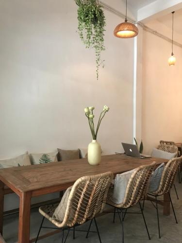 a dining room with a wooden table with chairs and a laptop at Sacred Lotus - Vegan Café X Hostel in Phnom Penh