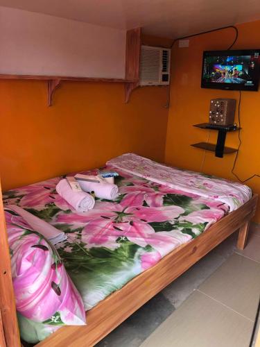 a bed with pink flowers on it in a room at ALERTA ROOFTOP LODGE in Magdiwang