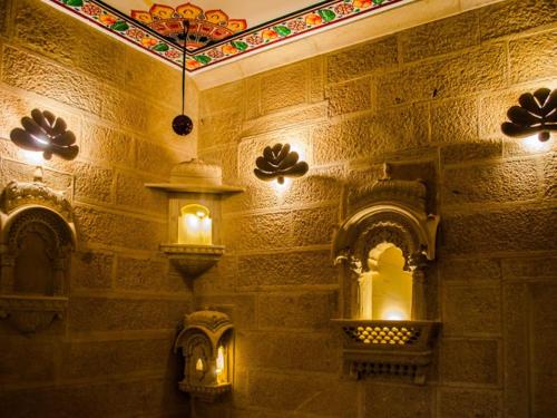 a room with a stone wall with a chandelier at Fort Villa in Jaisalmer