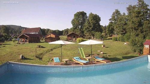 a swimming pool with chairs and umbrellas next to a house at chalets les 5 loups in Gerbépal