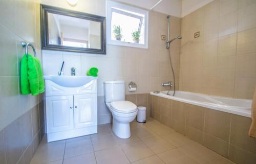 a bathroom with a toilet and a sink and a tub at Nissi Golden Sand lovely one bedroom apartment with spacious terrace and free parking in Ayia Napa